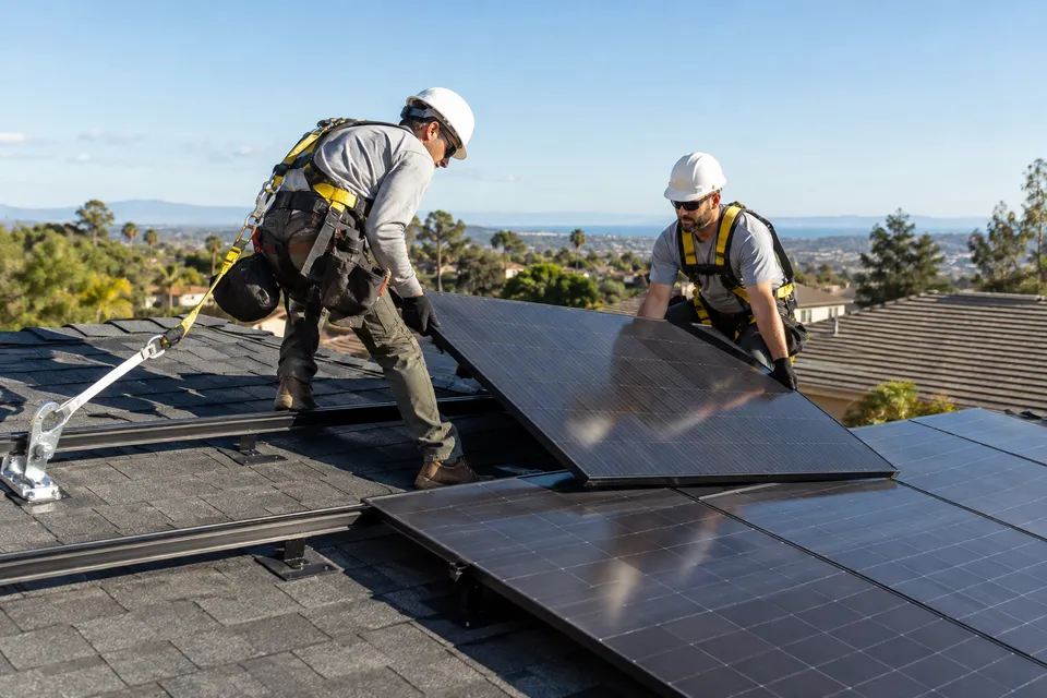 Illustrative campaign image: solar installers aligning rooftop photovoltaic panels.